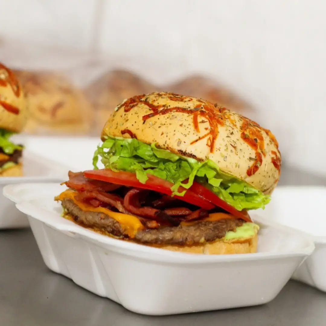 Hambúrguer com queijo, bacon, alface e tomate no pão coberto com queijo